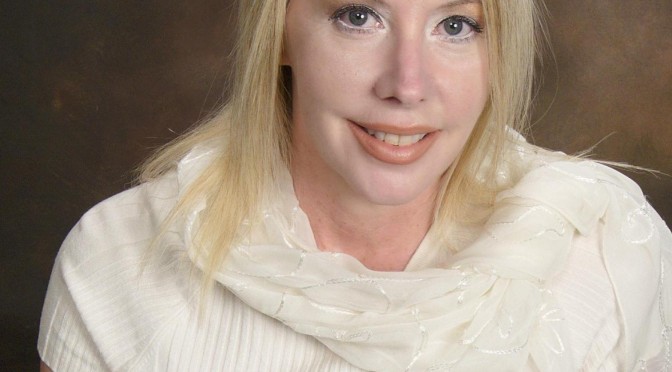 Portrait of a smiling woman with blonde hair wearing a white top and scarf.
